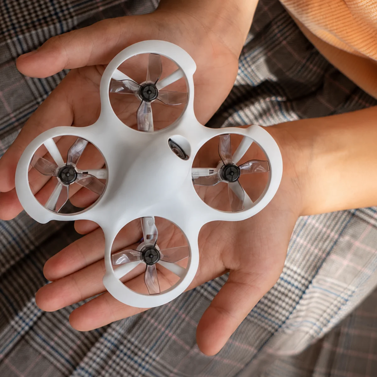 Palm-sized indoor drone held carefully in a young pilot's hands