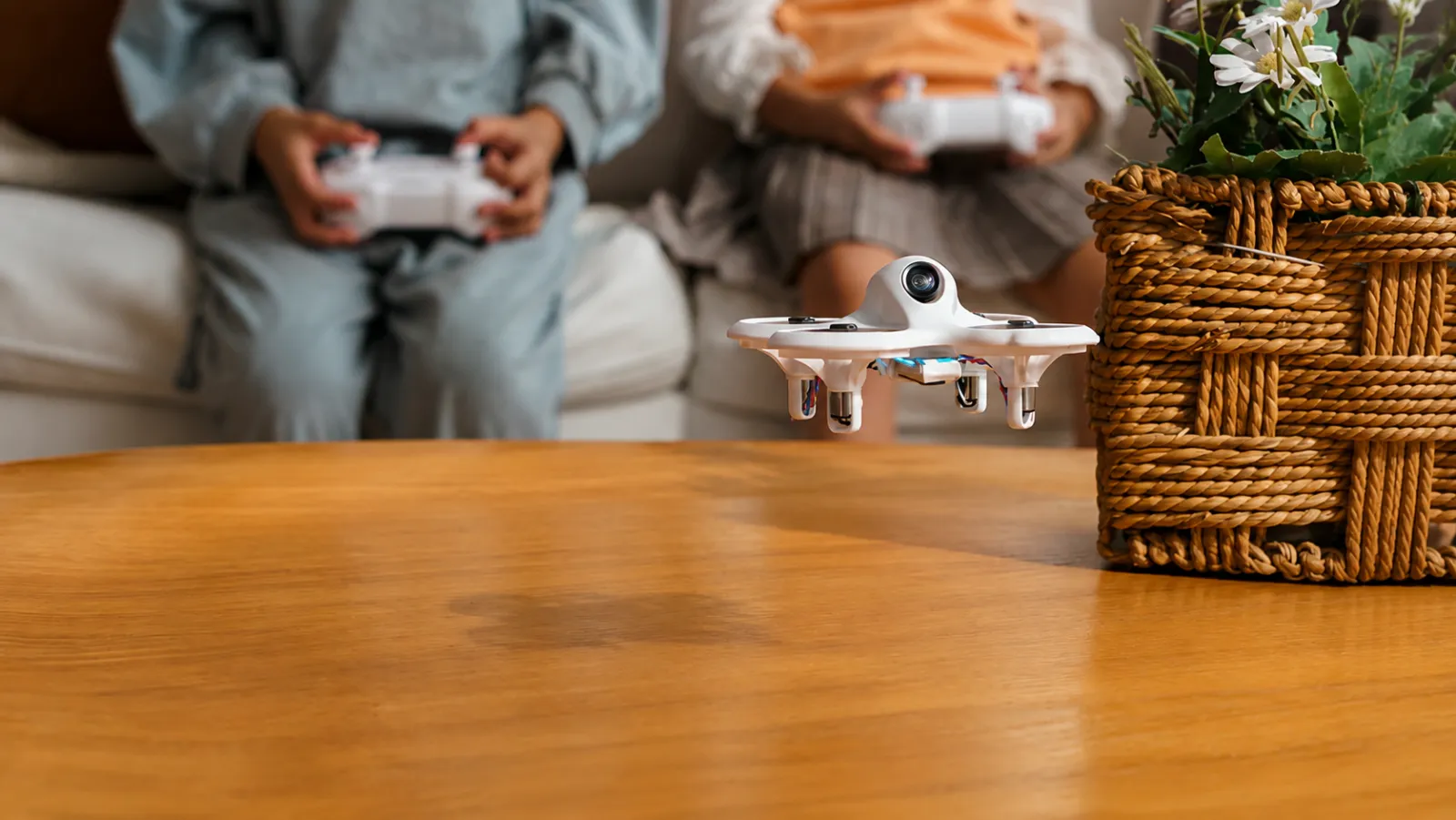 Two children flying a nano drone together in a living room